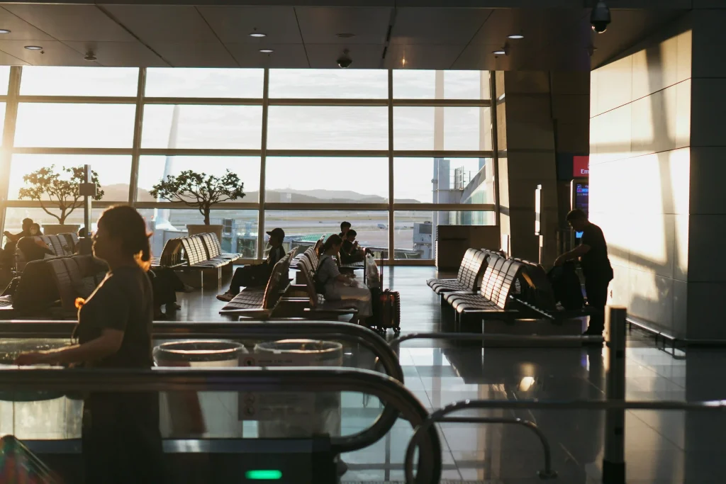 Travellers with suitcases waiting in an airport arrivals hall